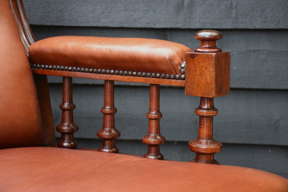 A 19th-century mahogany library armchair upholstered in buttoned brown leather with turned spindle arm supports and brass castors. View III
