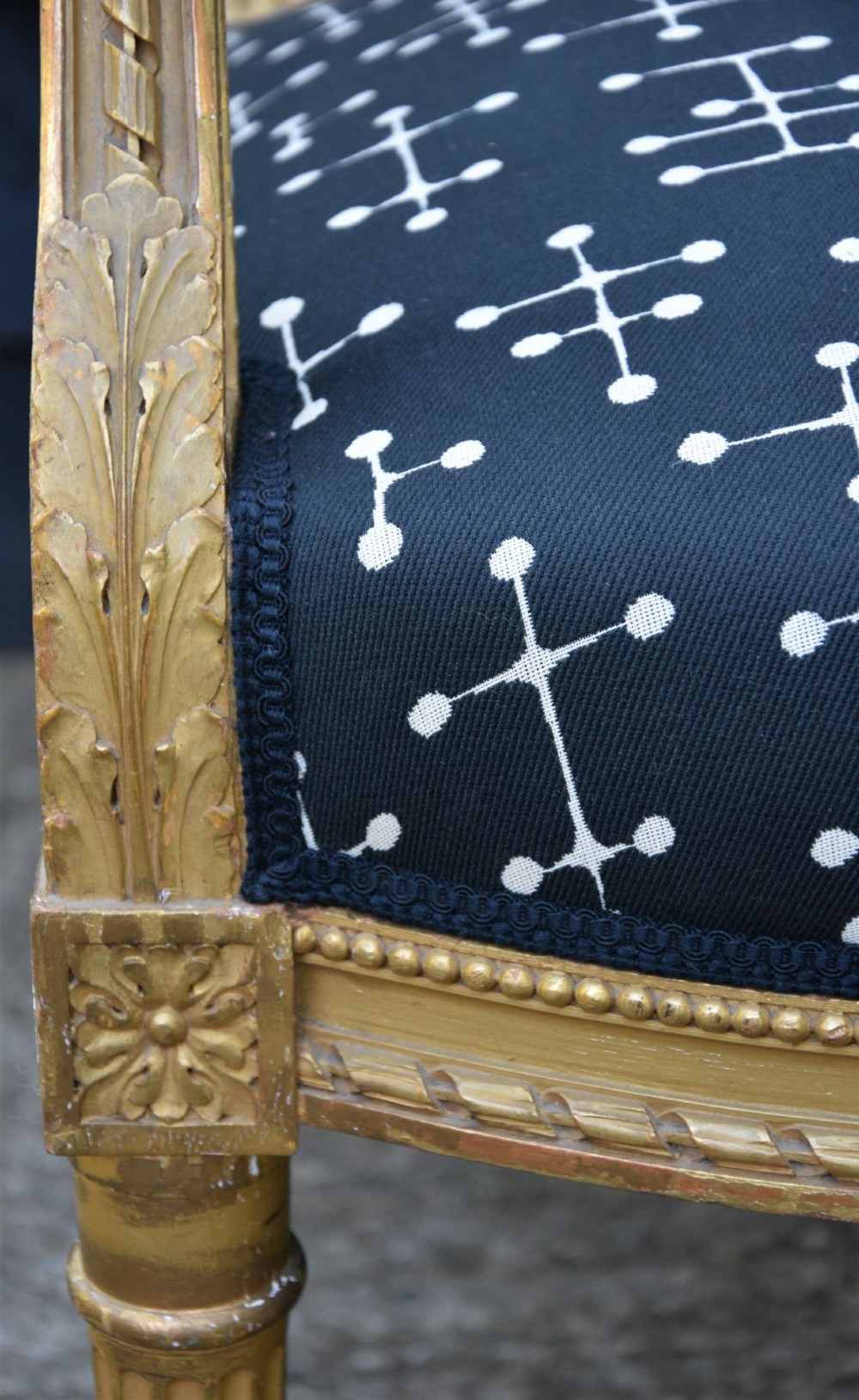 A French giltwood open armchair featuring a rectangular padded backrest, carved fluted legs, and navy blue upholstery with white geometric patterns. View VIII