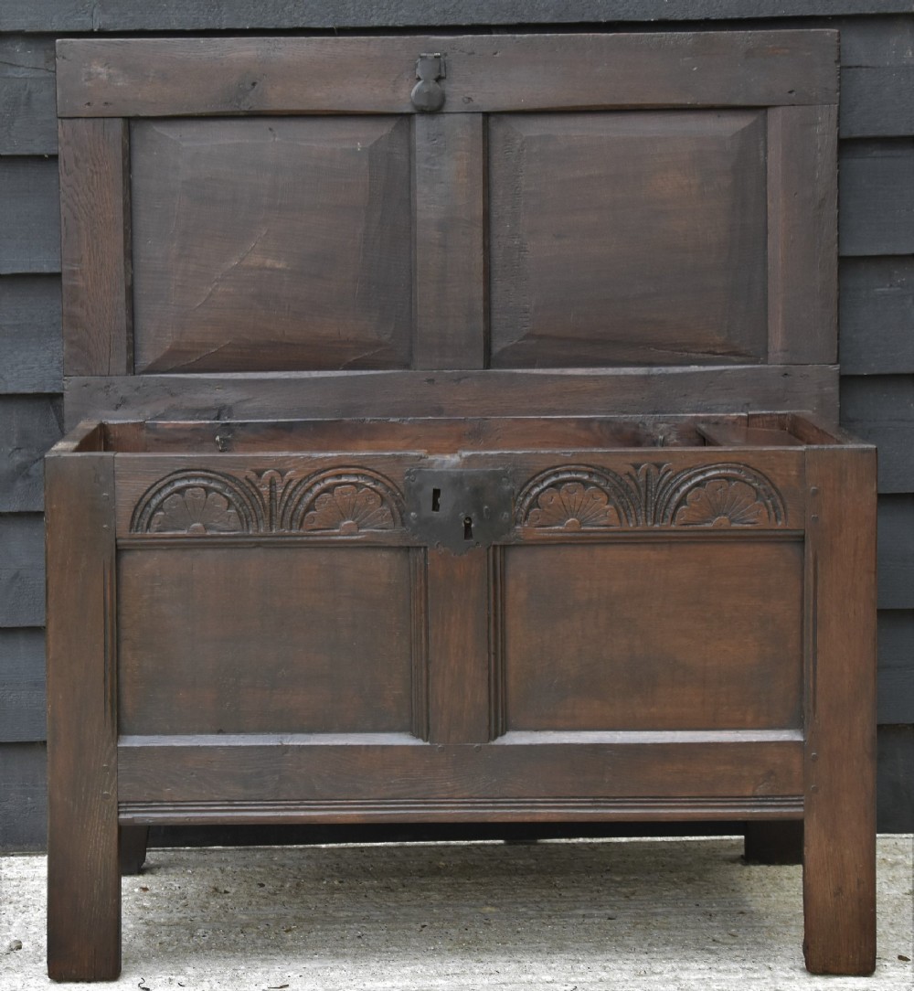 A small 17th-century dark oak coffer with a carved lunette frieze, twin front panels, peg joints, and a wrought iron lock plate. View II