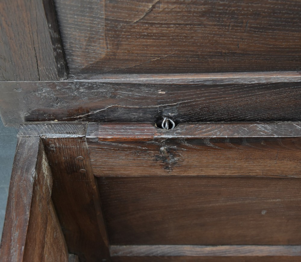 A small 17th-century dark oak coffer with a carved lunette frieze, twin front panels, peg joints, and a wrought iron lock plate. View III