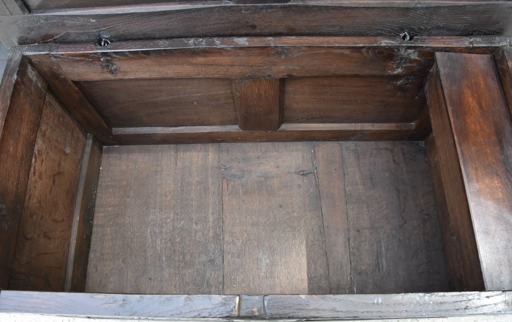 A small 17th-century dark oak coffer with a carved lunette frieze, twin front panels, peg joints, and a wrought iron lock plate. View IV