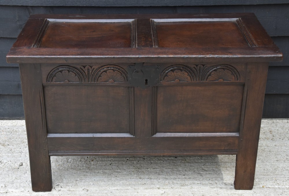 A small 17th-century dark oak coffer with a carved lunette frieze, twin front panels, peg joints, and a wrought iron lock plate. View VII