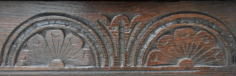 A small 17th-century dark oak coffer with a carved lunette frieze, twin front panels, peg joints, and a wrought iron lock plate. View VIII