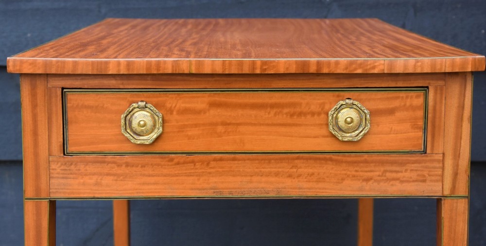 An antique Georgian satinwood lamp table featuring a single drawer with octagonal brass ring handles and slim square tapered legs. View II