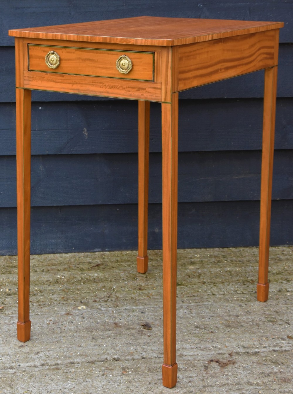 An antique Georgian satinwood lamp table featuring a single drawer with octagonal brass ring handles and slim square tapered legs. View IV