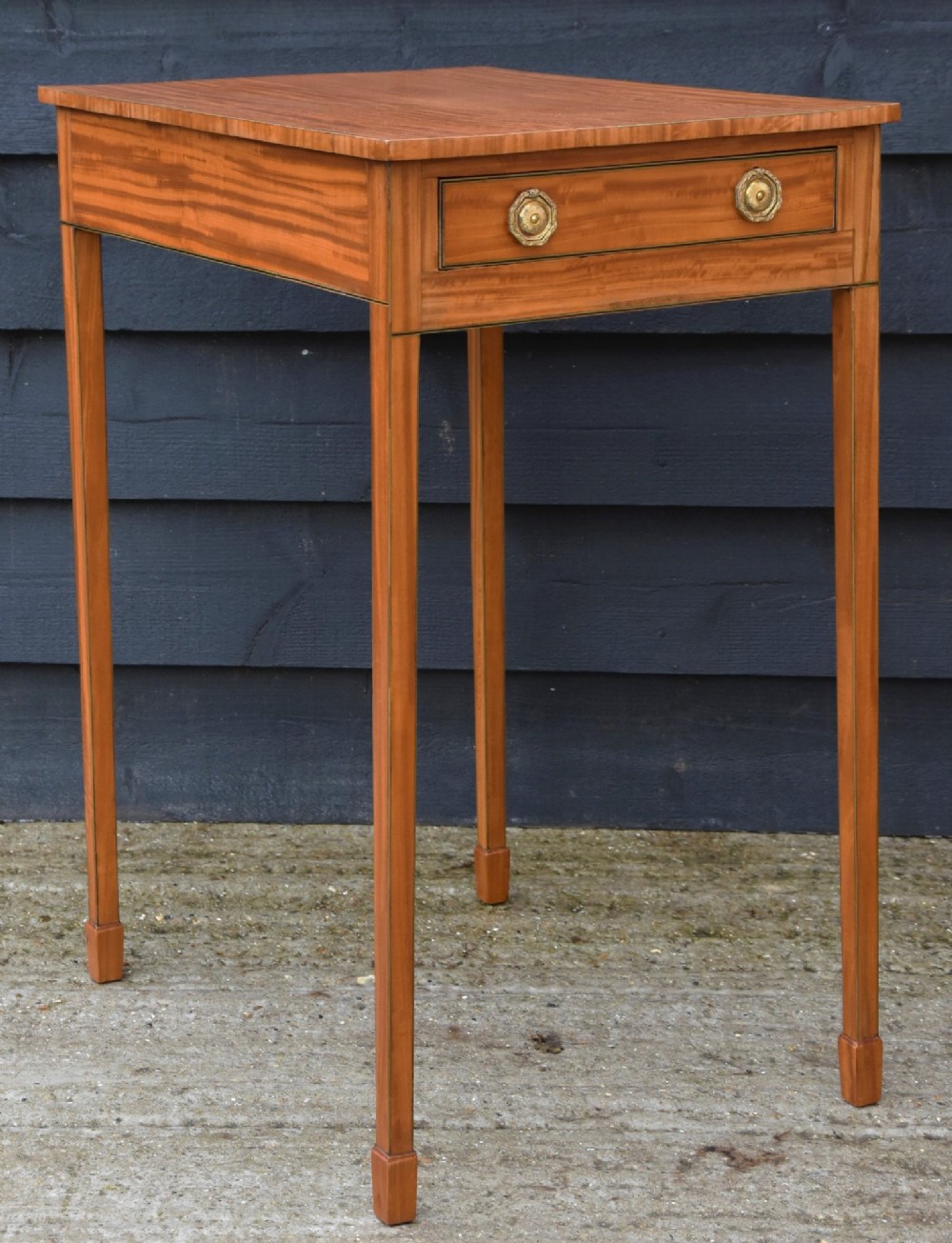 An antique Georgian satinwood lamp table featuring a single drawer with octagonal brass ring handles and slim square tapered legs. View V