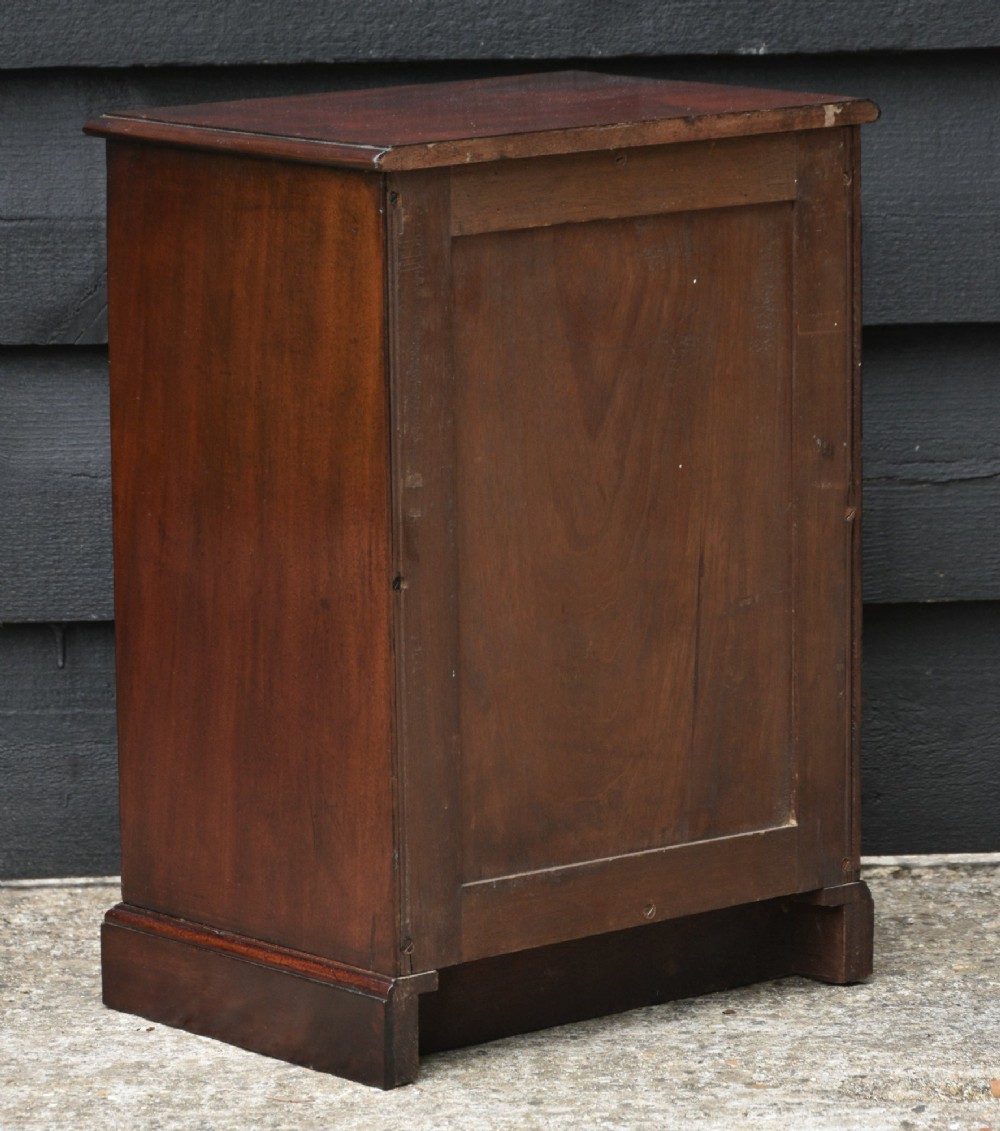 A Victorian mahogany miniature chest of drawers featuring eight drawers with turned wooden knobs and a solid plinth base. View IV