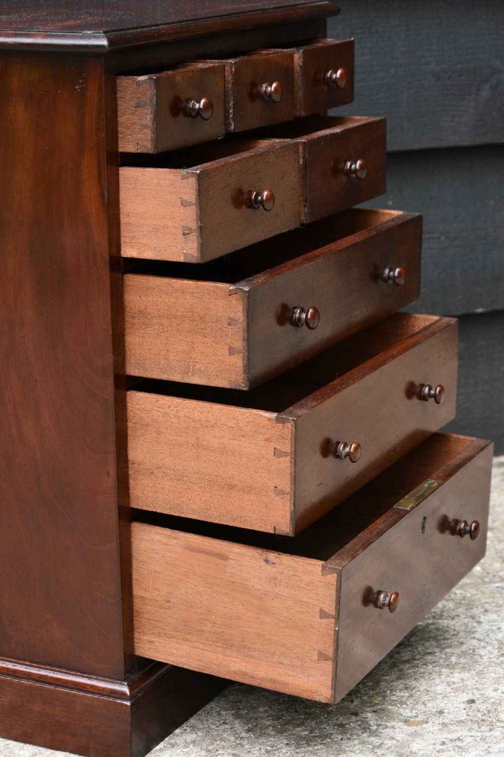 A Victorian mahogany miniature chest of drawers featuring eight drawers with turned wooden knobs and a solid plinth base. View V