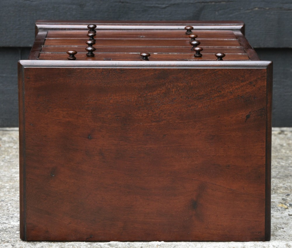 A Victorian mahogany miniature chest of drawers featuring eight drawers with turned wooden knobs and a solid plinth base. View VII