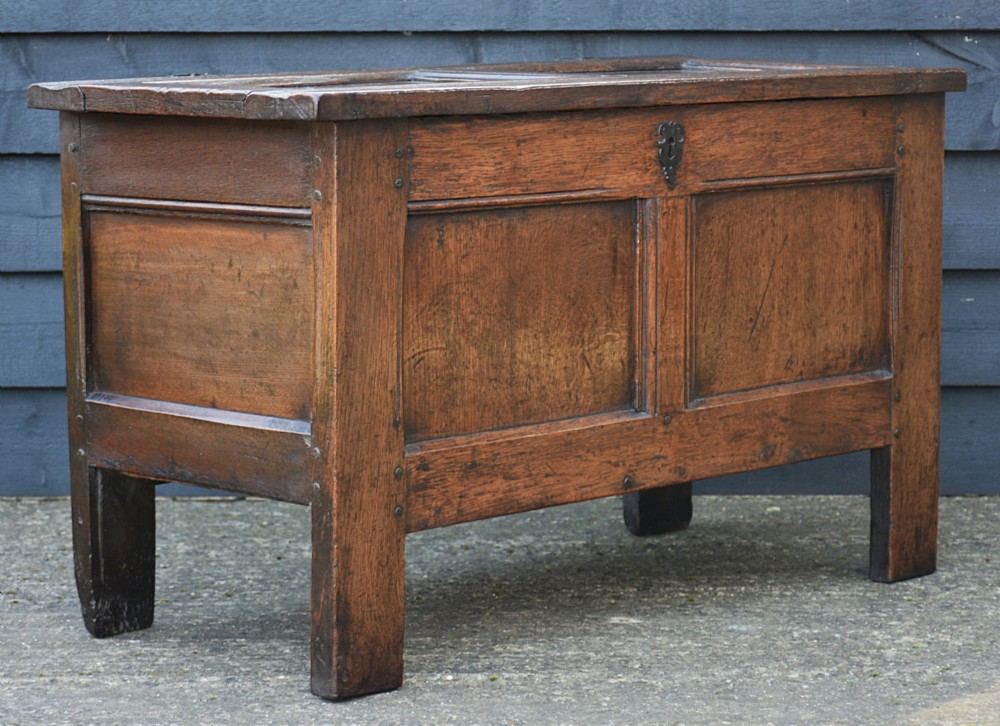 A seventeenth-century oak coffer featuring a twin-panelled front, moulded lid, stile legs, and a central iron keyhole escutcheon. View II