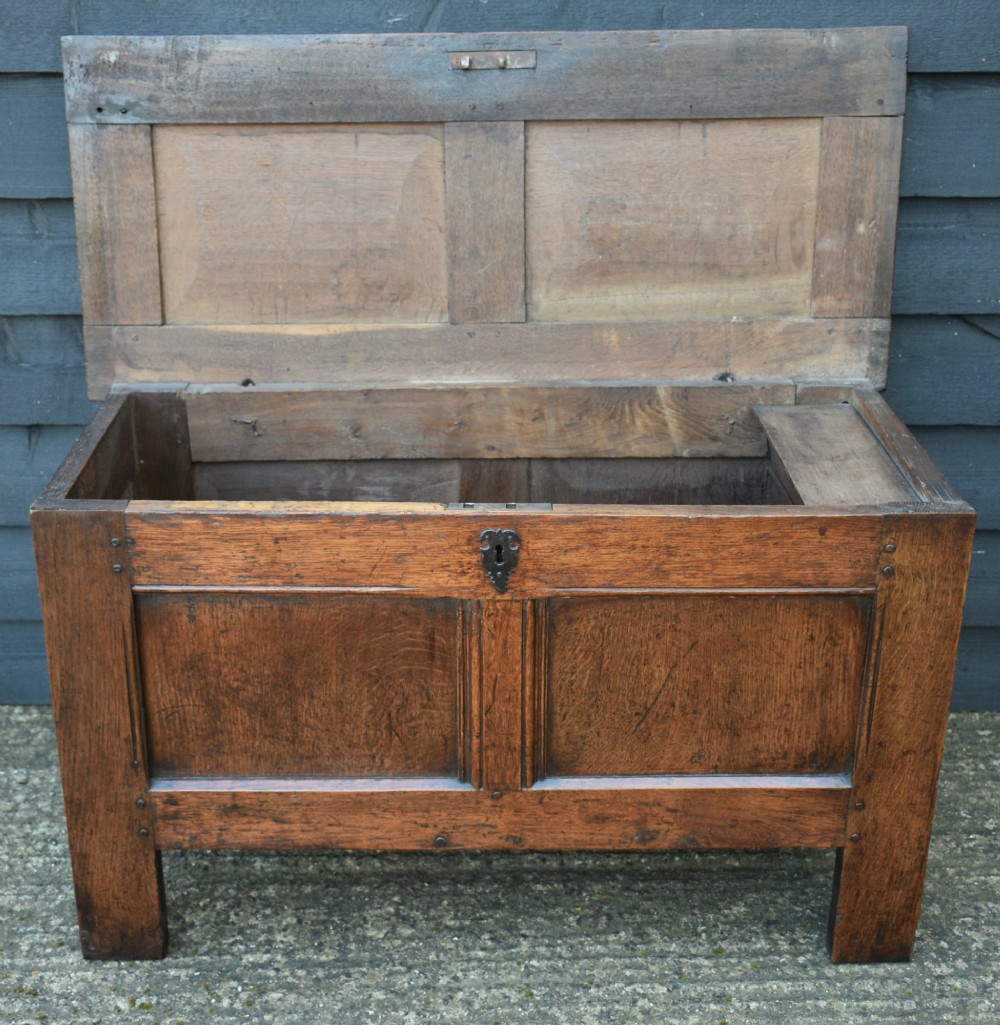 A seventeenth-century oak coffer featuring a twin-panelled front, moulded lid, stile legs, and a central iron keyhole escutcheon. View IV