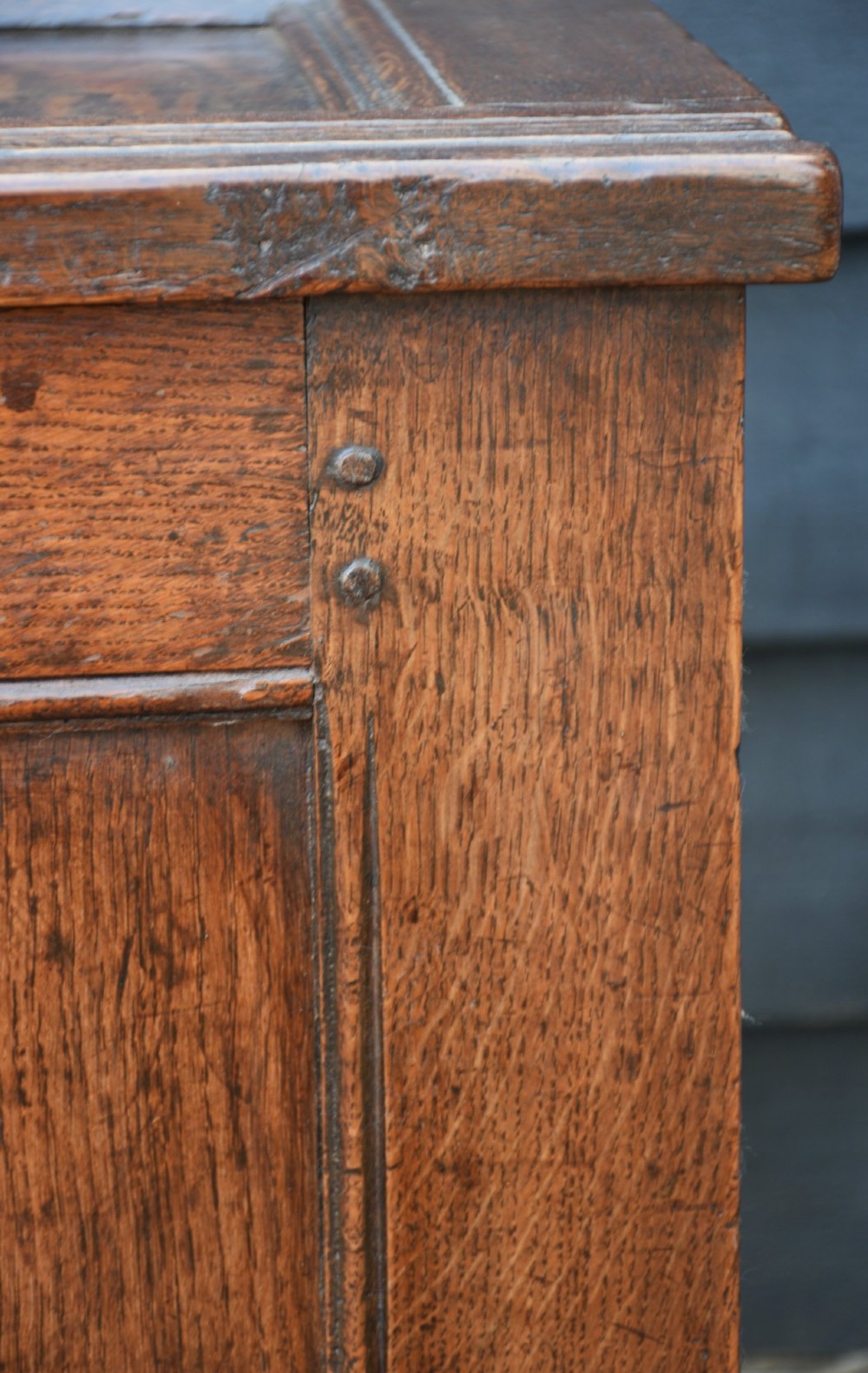 A seventeenth-century oak coffer featuring a twin-panelled front, moulded lid, stile legs, and a central iron keyhole escutcheon. View VIII
