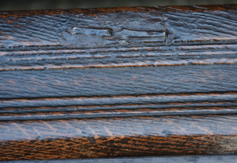 A seventeenth-century oak coffer featuring a twin-panelled front, moulded lid, stile legs, and a central iron keyhole escutcheon. View IX