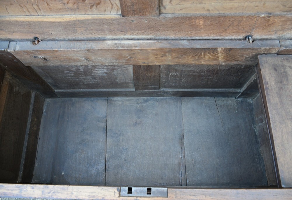 A seventeenth-century oak coffer featuring a twin-panelled front, moulded lid, stile legs, and a central iron keyhole escutcheon. View X