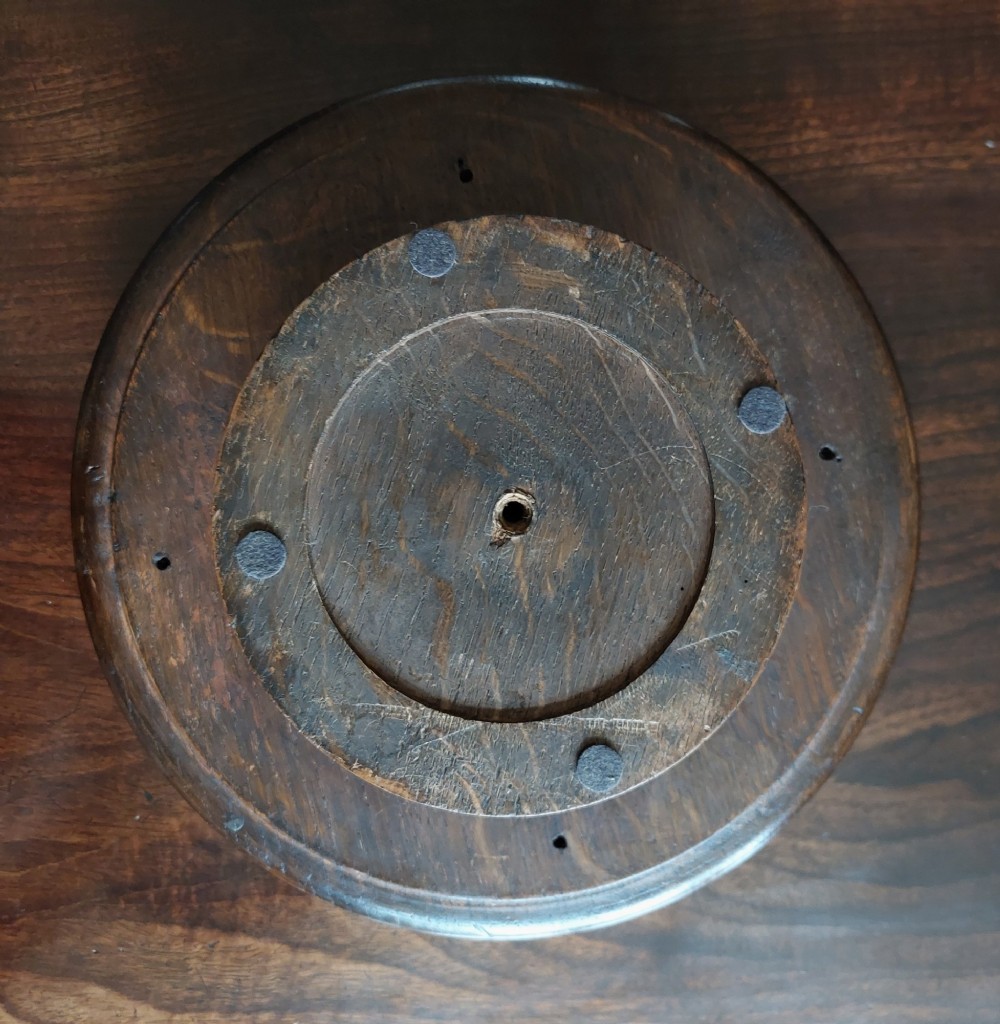 A circular dark carved oak fruit bowl on a low pedestal base decorated with a relief band of carved grapevines. View IV