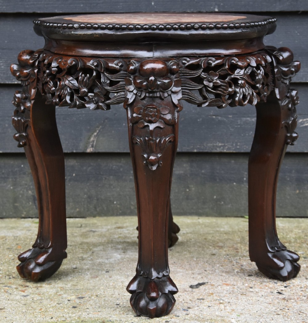 A circular 19th-century Chinese dark rosewood low table featuring an inset marble top, detailed floral openwork aprons, and cabriole legs ending in carved feet.
