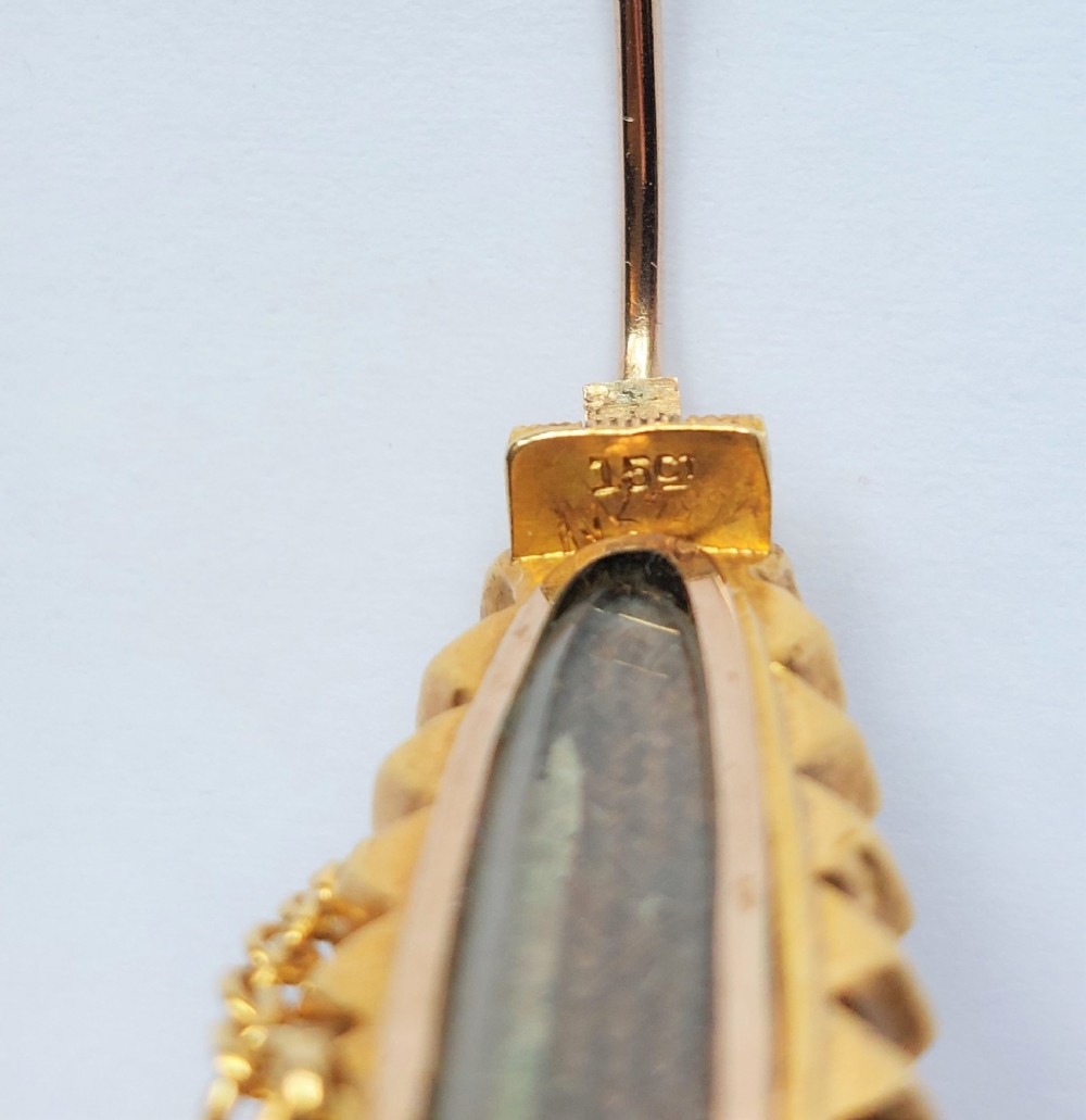 An elongated navette-shaped Victorian 15ct gold brooch with a black onyx center, central seed pearl starburst, and seed pearl border. View IV