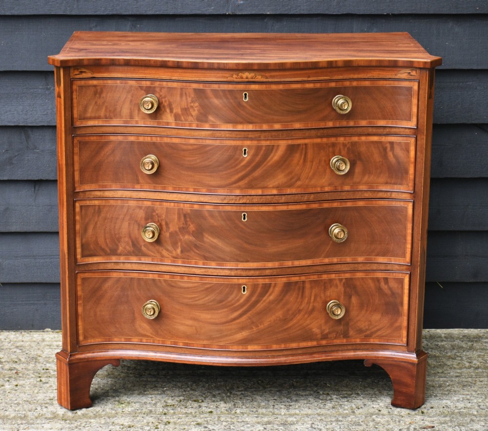 A late 18th-century Georgian mahogany serpentine chest of drawers featuring four graduated drawers with brass handles and bracket feet.