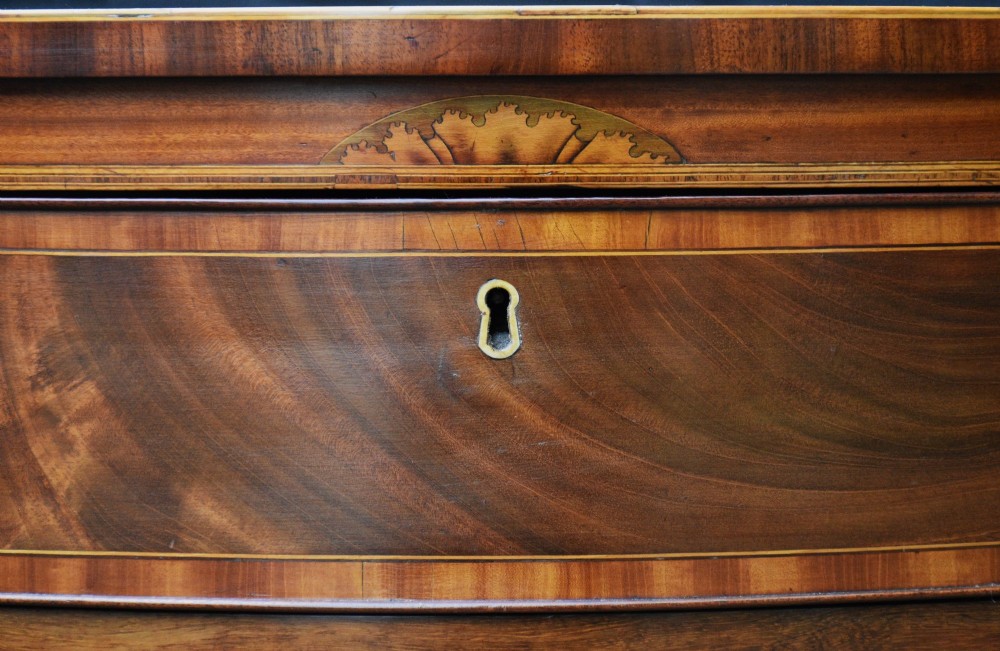 A late 18th-century Georgian mahogany serpentine chest of drawers featuring four graduated drawers with brass handles and bracket feet. View II