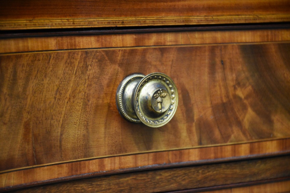 A late 18th-century Georgian mahogany serpentine chest of drawers featuring four graduated drawers with brass handles and bracket feet. View III