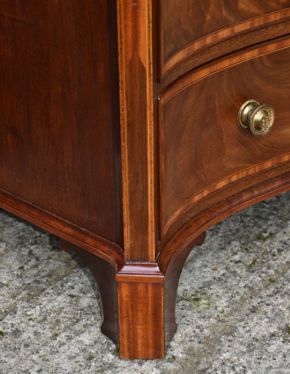 A late 18th-century Georgian mahogany serpentine chest of drawers featuring four graduated drawers with brass handles and bracket feet. View IV