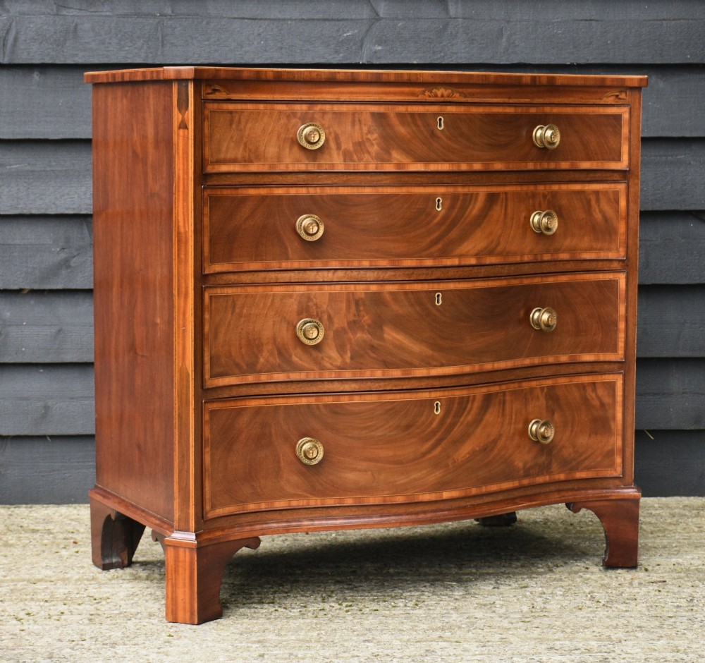 A late 18th-century Georgian mahogany serpentine chest of drawers featuring four graduated drawers with brass handles and bracket feet. View IX