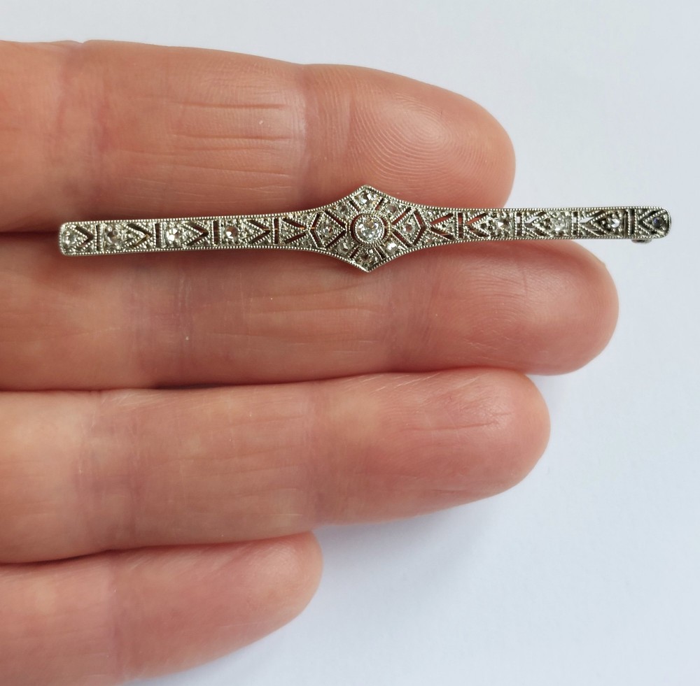 An Art Deco elongated platinum bar brooch adorned with milgrain-bordered geometric openwork and central diamonds. View III