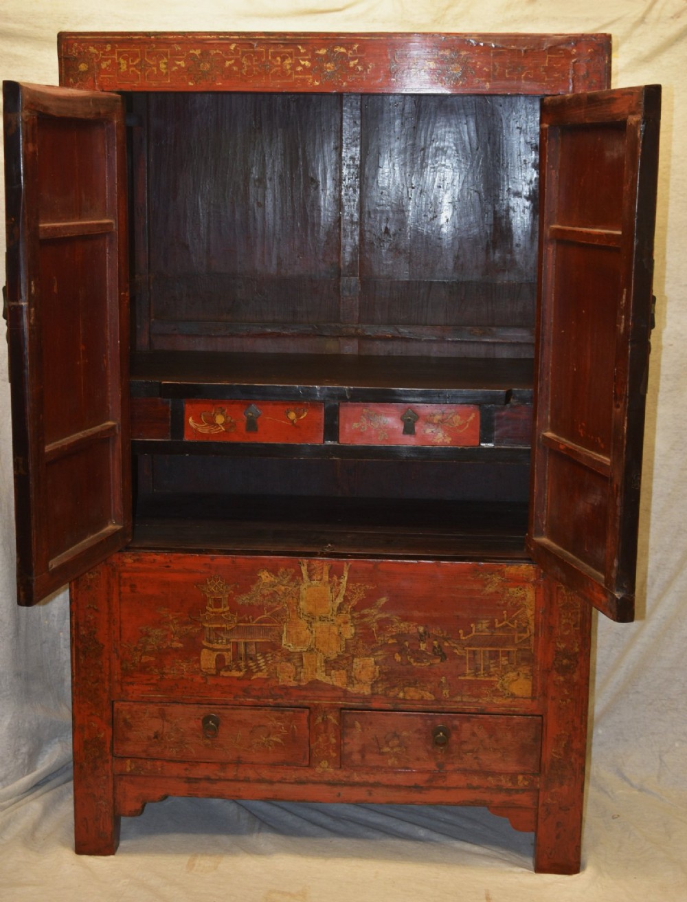 An early nineteenth-century Chinese red lacquered cabinet decorated with gilded landscape scenes, a brass faceplate, and two lower drawers. View II