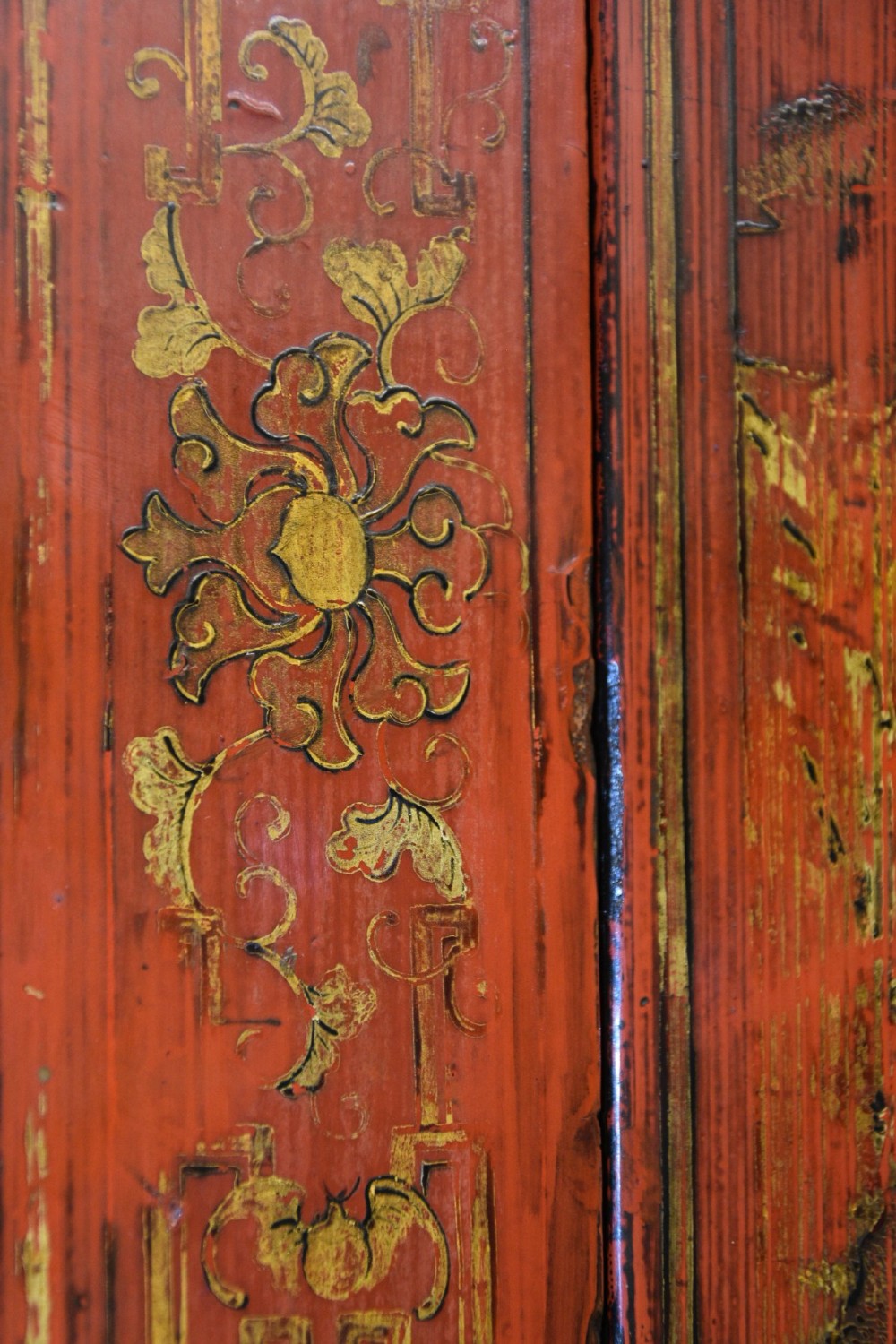 An early nineteenth-century Chinese red lacquered cabinet decorated with gilded landscape scenes, a brass faceplate, and two lower drawers. View VII