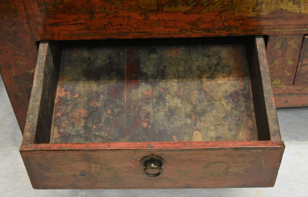 An early nineteenth-century Chinese red lacquered cabinet decorated with gilded landscape scenes, a brass faceplate, and two lower drawers. View VIII