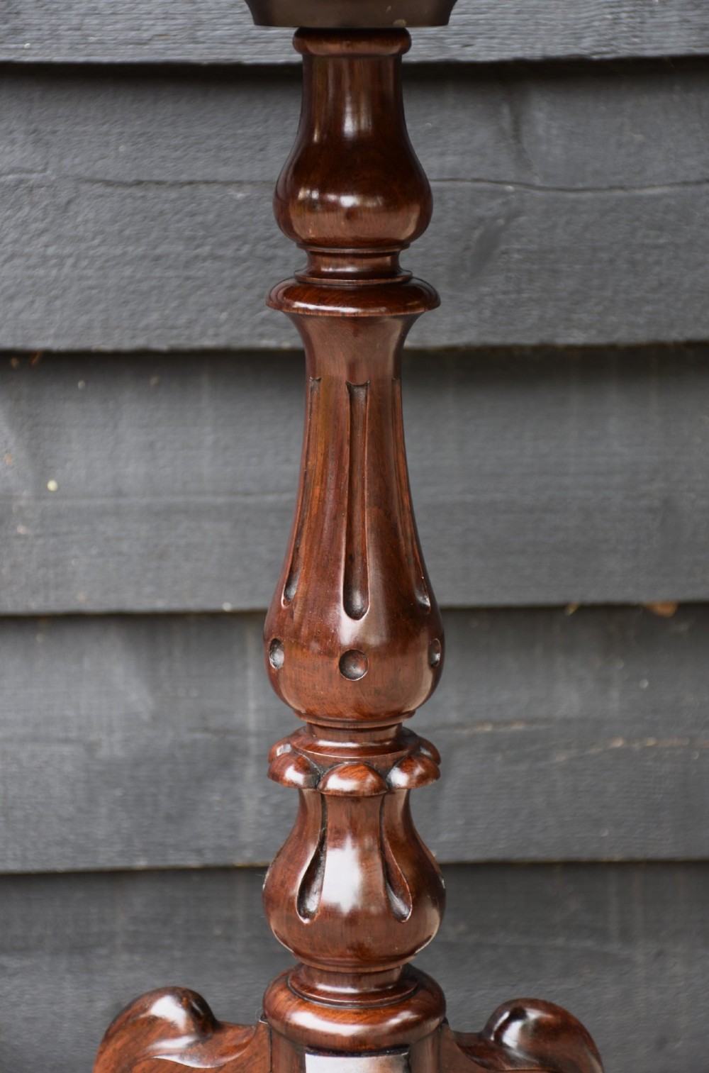 A circular 19th-century rosewood lamp table featuring a bookmatched wood grain top resting on a carved pedestal stem with tripod legs. View IV