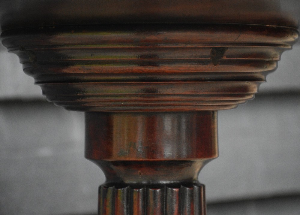 A circular Regency mahogany tea table featuring a moulded edge top, fluted central pedestal, and three reeded tripod legs with brass paw feet and castors. View VII