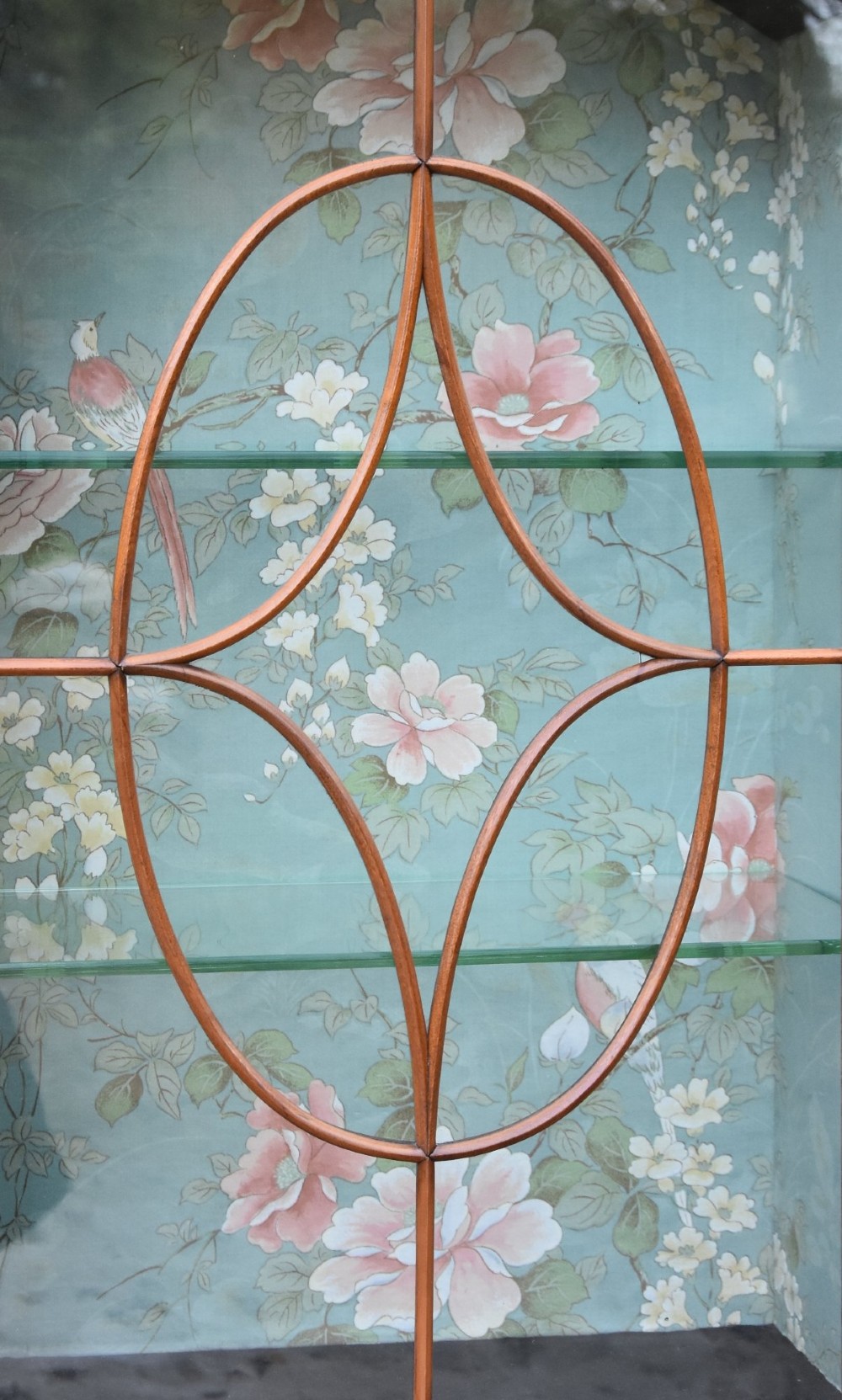 An Edwardian satinwood display cabinet featuring three astragal glazed doors, floral fabric interior lining, and inlaid lower cupboard doors raised on square tapered legs. View VII