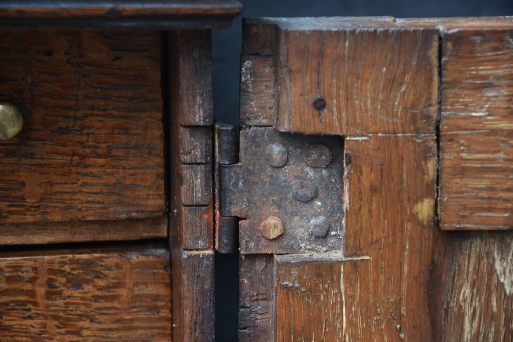 An early 18th-century oak spice cupboard featuring a single fielded panel door, brass escutcheon, and moulded top and base trim. View III