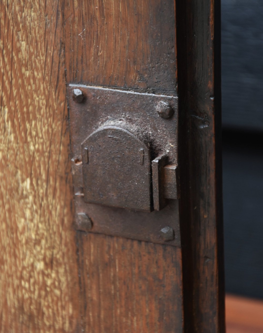 An early 18th-century oak spice cupboard featuring a single fielded panel door, brass escutcheon, and moulded top and base trim. View IV