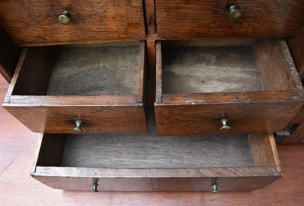 An early 18th-century oak spice cupboard featuring a single fielded panel door, brass escutcheon, and moulded top and base trim. View V
