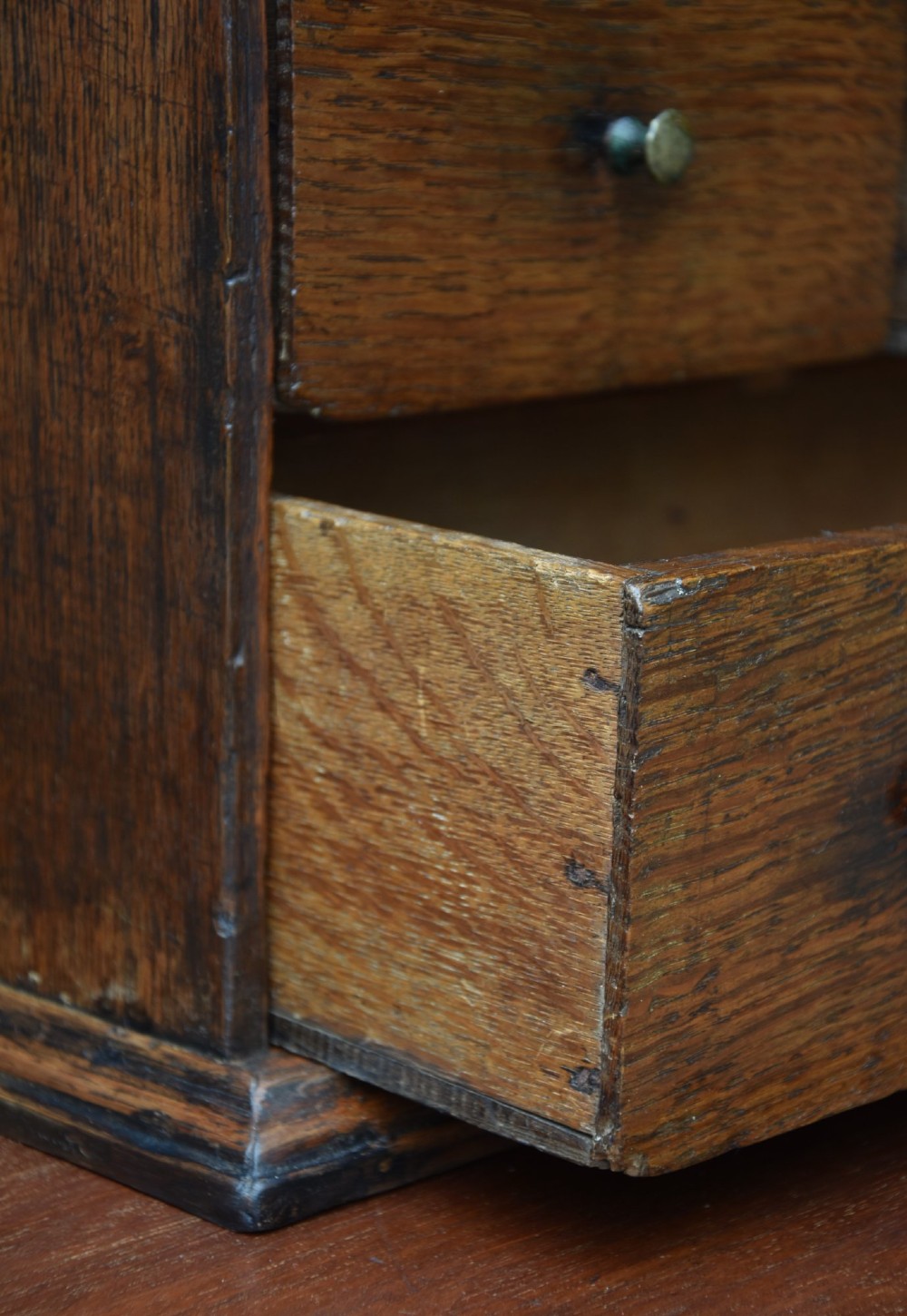 An early 18th-century oak spice cupboard featuring a single fielded panel door, brass escutcheon, and moulded top and base trim. View VI