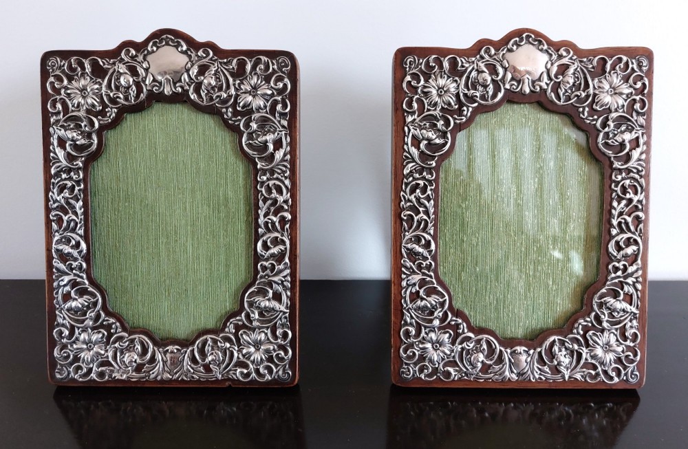 A pair of rectangular Edwardian photo frames featuring pierced scrollwork silver fronts mounted onto dark hardwood backings.