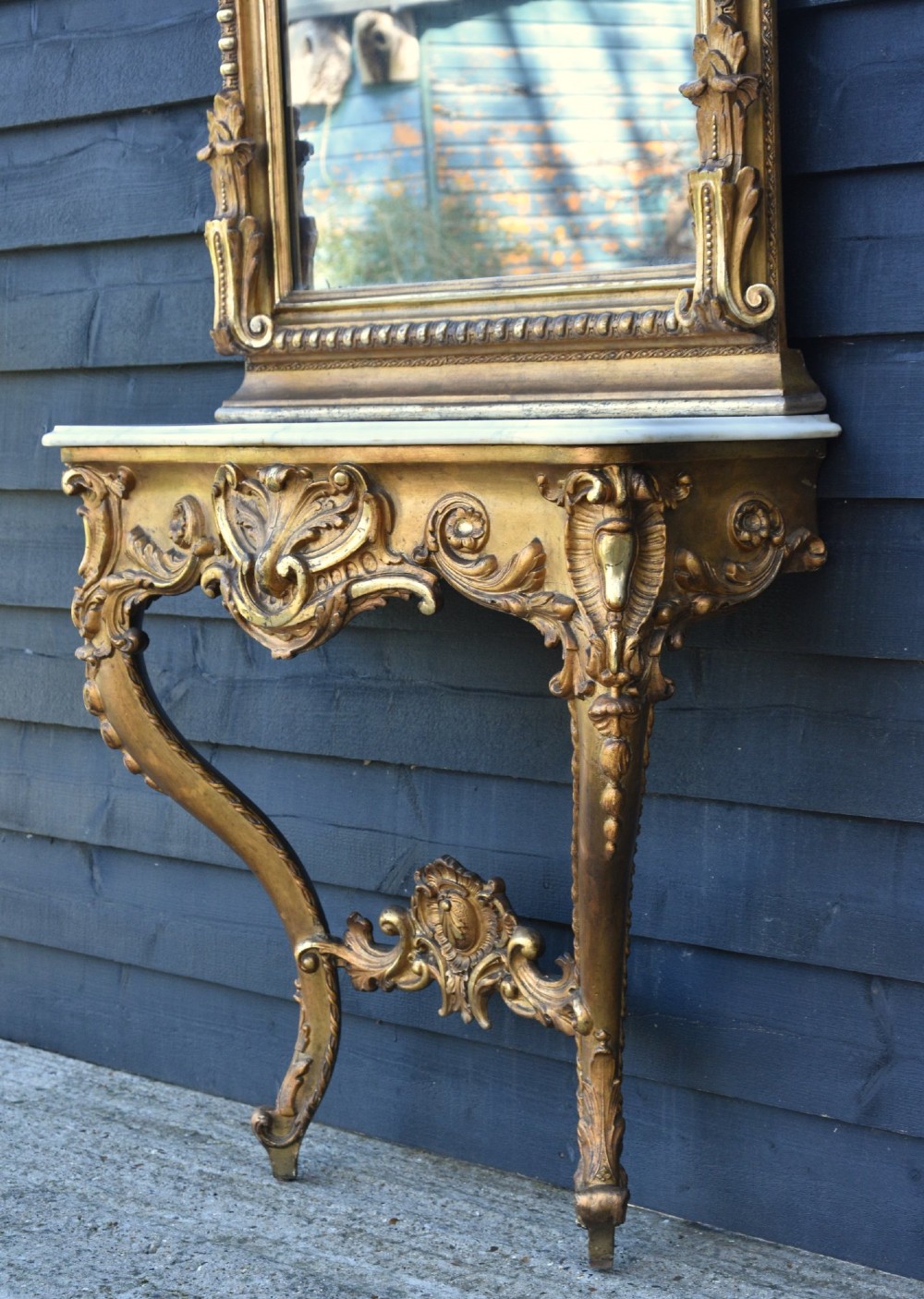 A French giltwood pier mirror featuring a carved rocaille cresting, mounted above a matching marble-topped console table with cabriole legs. View II