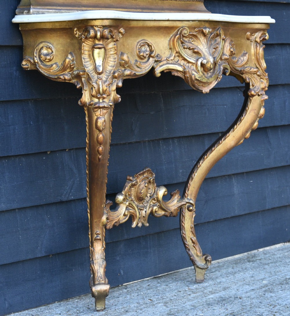 A French giltwood pier mirror featuring a carved rocaille cresting, mounted above a matching marble-topped console table with cabriole legs. View III