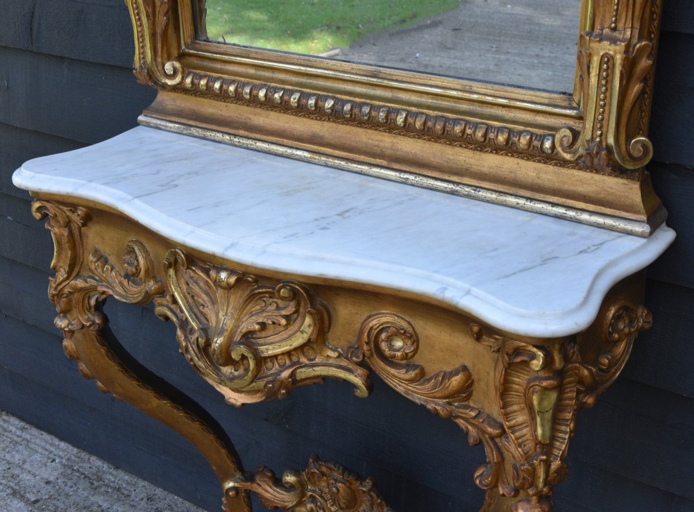 A French giltwood pier mirror featuring a carved rocaille cresting, mounted above a matching marble-topped console table with cabriole legs. View V