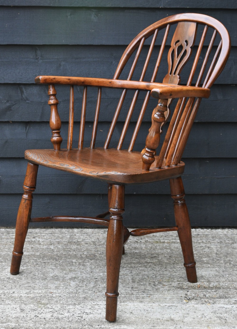A 19th-century English Windsor armchair made from yew and elm wood featuring a hoop back, a central pierced splat, turned legs, and a crinoline stretcher. View IV