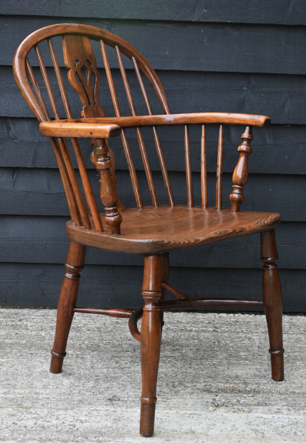 A 19th-century English Windsor armchair made from yew and elm wood featuring a hoop back, a central pierced splat, turned legs, and a crinoline stretcher. View V