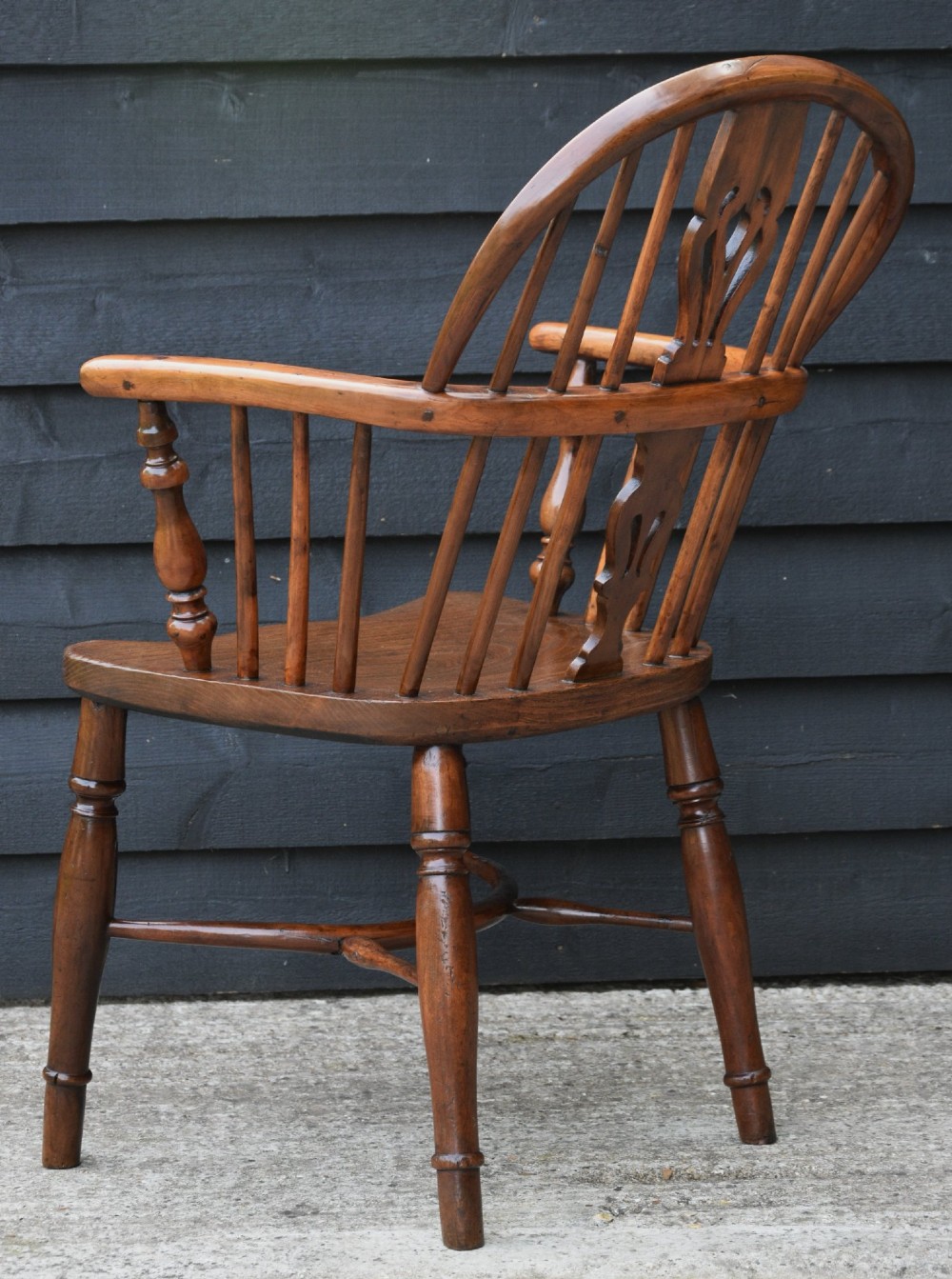 A 19th-century English Windsor armchair made from yew and elm wood featuring a hoop back, a central pierced splat, turned legs, and a crinoline stretcher. View VI