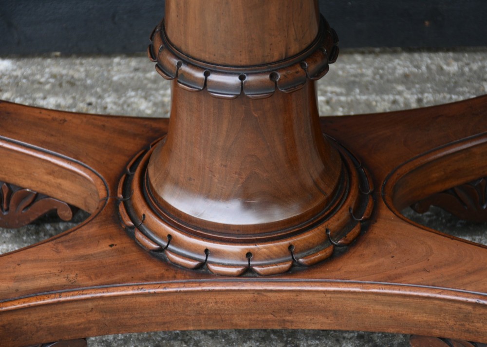 A 19th-century William IV mahogany fold-over card table featuring a rectangular swivel top resting on a tapered pedestal column and quadform base with carved lion paw feet. View II
