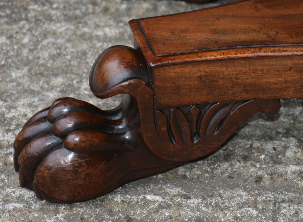 A 19th-century William IV mahogany fold-over card table featuring a rectangular swivel top resting on a tapered pedestal column and quadform base with carved lion paw feet. View IV