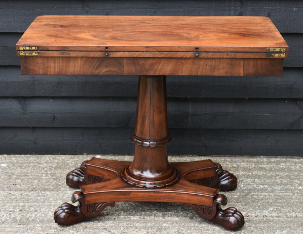 A 19th-century William IV mahogany fold-over card table featuring a rectangular swivel top resting on a tapered pedestal column and quadform base with carved lion paw feet. View VII