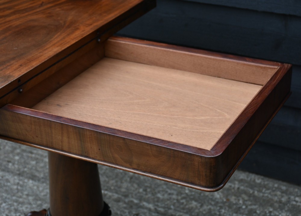A 19th-century William IV mahogany fold-over card table featuring a rectangular swivel top resting on a tapered pedestal column and quadform base with carved lion paw feet. View VIII