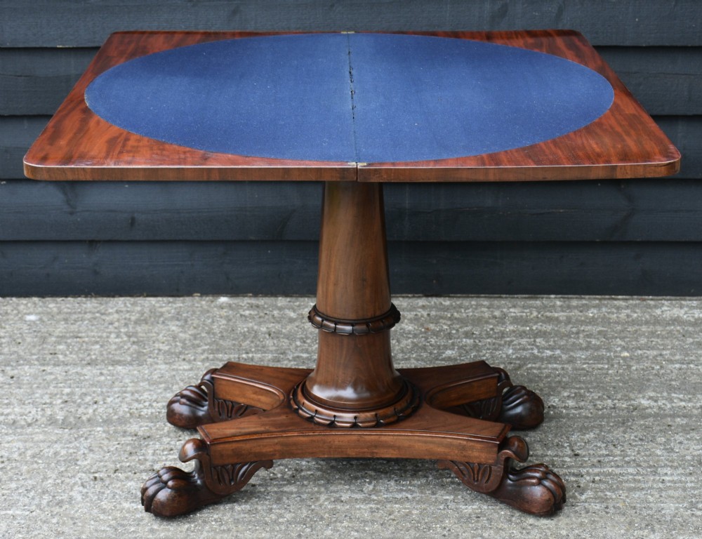 A 19th-century William IV mahogany fold-over card table featuring a rectangular swivel top resting on a tapered pedestal column and quadform base with carved lion paw feet. View IX