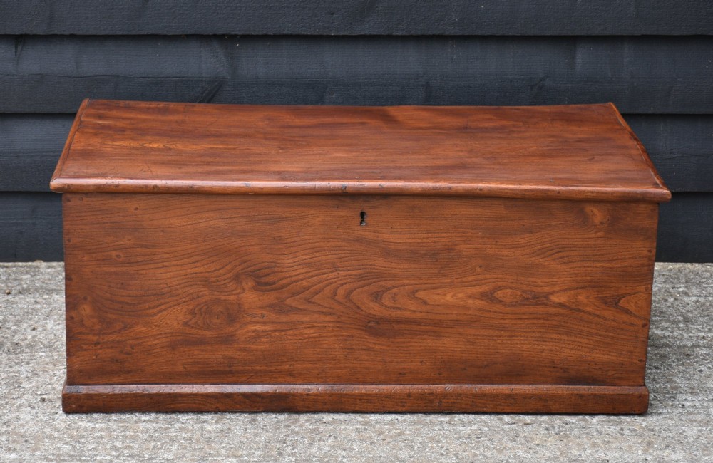 A rectangular Georgian elm blanket box featuring a hinged top lid, front keyhole, side iron handles, and a simple plinth base. View II